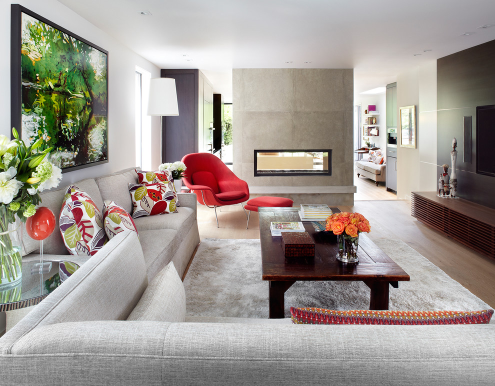 This is an example of a large contemporary living room in Toronto with light hardwood floors, a two-sided fireplace and a wall-mounted tv.