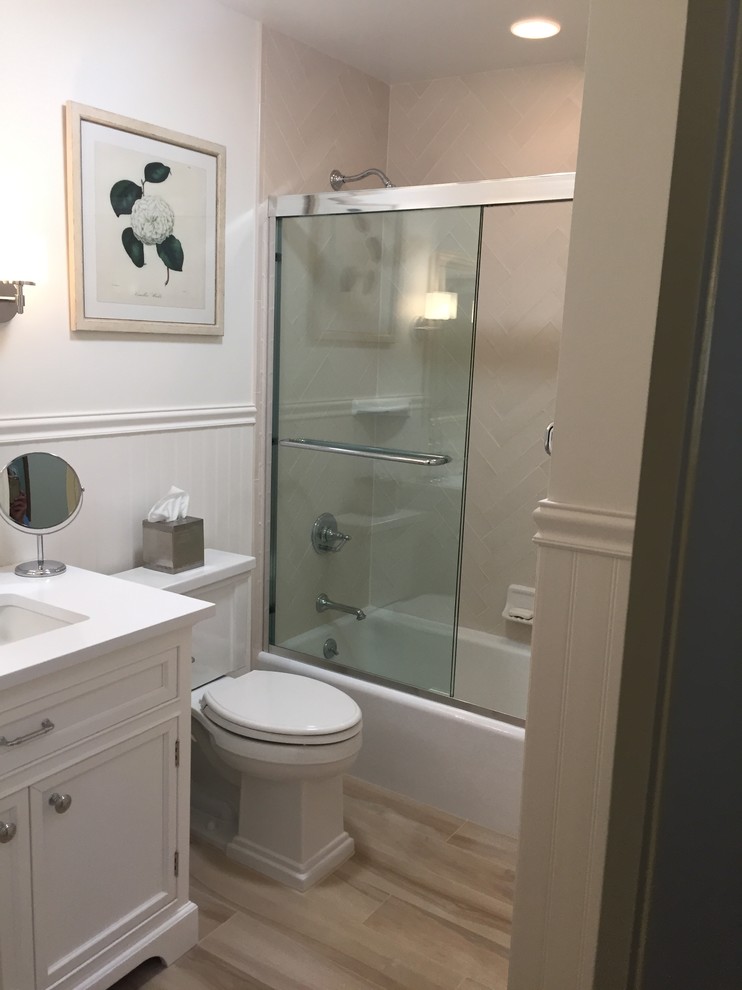 Photo of a small traditional 3/4 bathroom in New York with beaded inset cabinets, white cabinets, a drop-in tub, a shower/bathtub combo, a two-piece toilet, beige tile, subway tile, beige walls, ceramic floors, a drop-in sink, quartzite benchtops, white benchtops and a sliding shower screen.