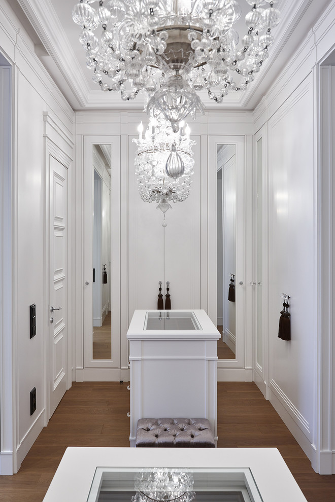 This is an example of a transitional gender-neutral dressing room in Moscow with flat-panel cabinets, white cabinets, medium hardwood floors and brown floor.