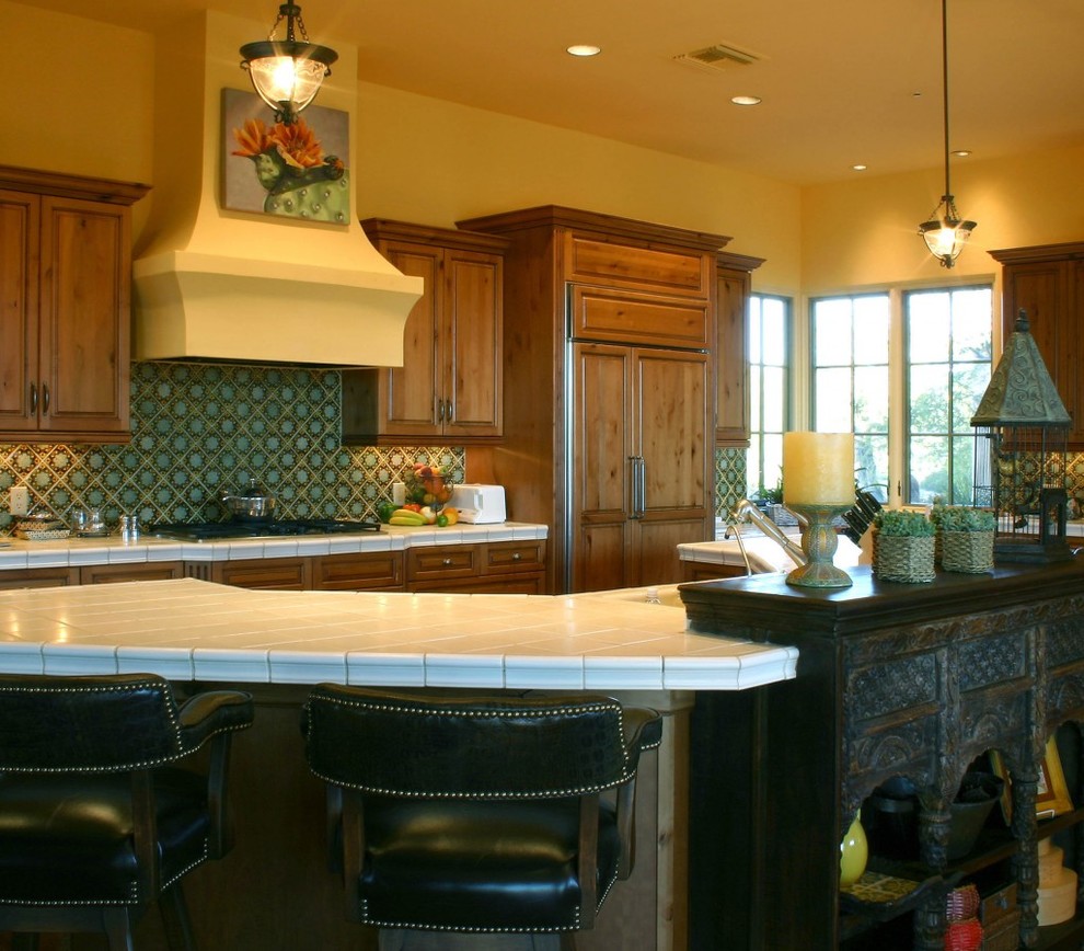 Inspiration for a large u-shaped eat-in kitchen in Phoenix with beaded inset cabinets, medium wood cabinets, tile benchtops, green splashback, ceramic splashback, panelled appliances, terra-cotta floors and with island.