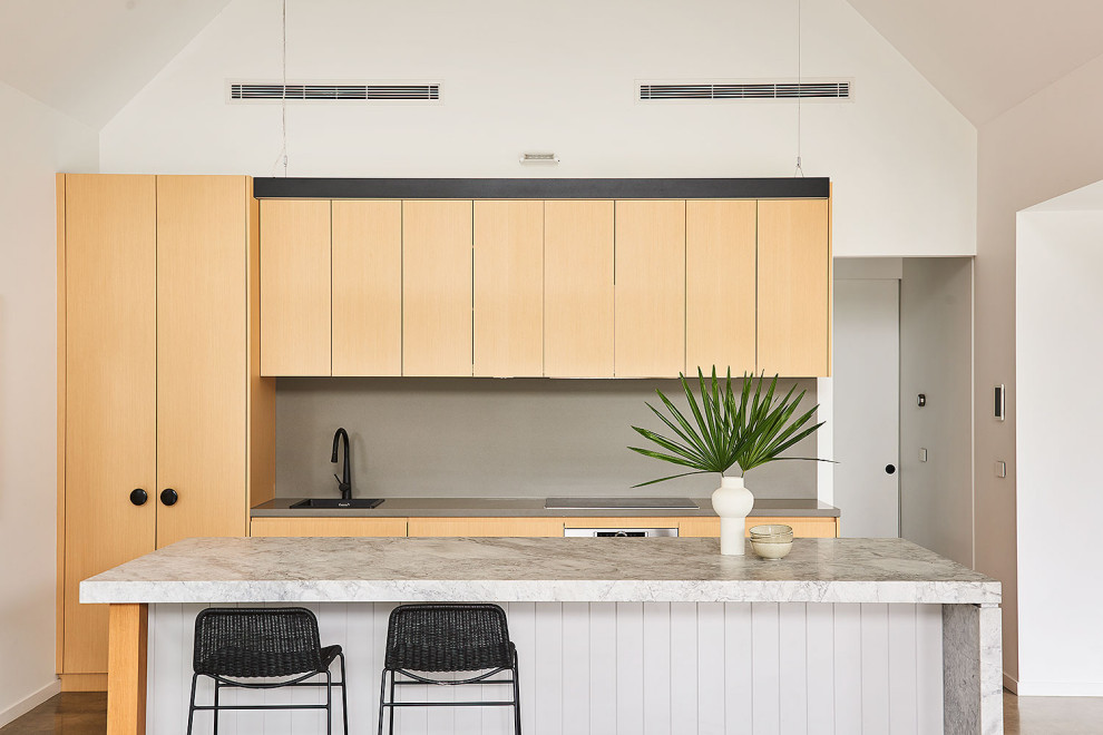 Mid-sized tropical galley eat-in kitchen in Geelong with a drop-in sink, light wood cabinets, quartz benchtops, grey splashback, engineered quartz splashback, concrete floors, with island, grey floor, white benchtop and vaulted.