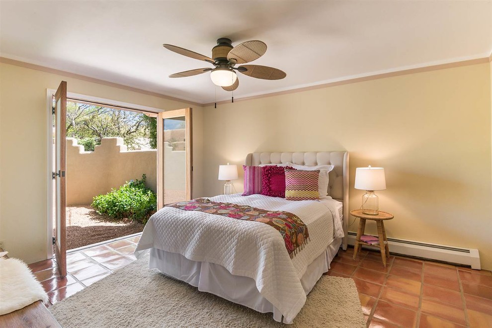 Mid-sized master bedroom in Other with yellow walls, terra-cotta floors, no fireplace and orange floor.