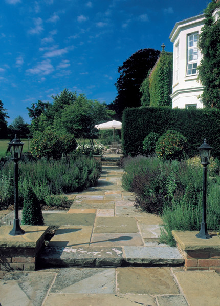 This is an example of a large traditional courtyard full sun formal garden for spring in London with natural stone pavers.