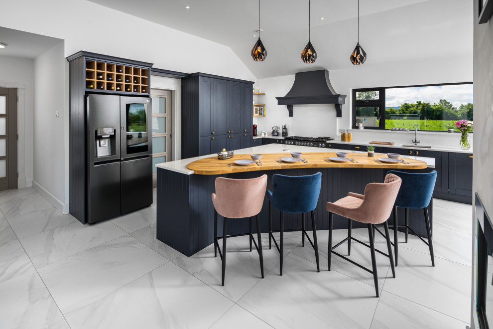 Expansive traditional l-shaped open plan kitchen in Other with an undermount sink, shaker cabinets, blue cabinets, quartzite benchtops, white splashback, black appliances, with island, grey floor and white benchtop.