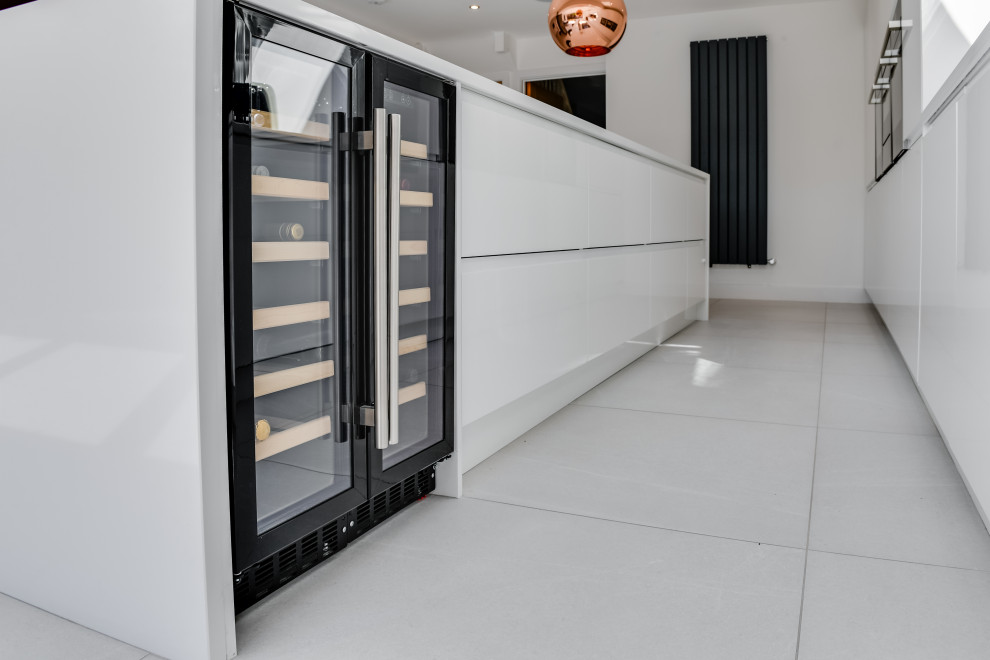Exempel på ett stort modernt vit linjärt vitt kök och matrum, med en undermonterad diskho, släta luckor, vita skåp, svart stänkskydd, svarta vitvaror, en köksö och vitt golv