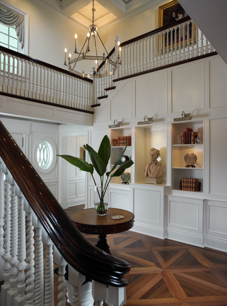 This is an example of a traditional foyer in Miami with white walls, medium hardwood floors and brown floor.