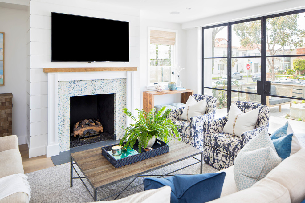 Mid-sized beach style open concept living room in Orange County with white walls, medium hardwood floors, a standard fireplace, a tile fireplace surround, brown floor and a wall-mounted tv.