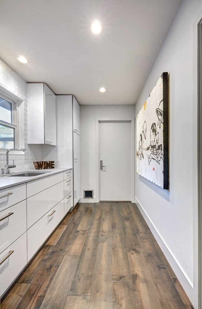 Design ideas for a mid-sized modern galley utility room in Sacramento with an undermount sink, flat-panel cabinets, white cabinets, quartz benchtops, grey walls, porcelain floors and a side-by-side washer and dryer.