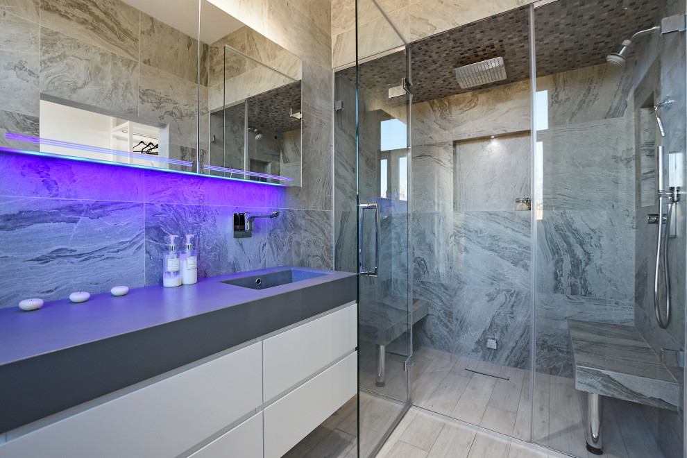 Design ideas for a large contemporary master bathroom in London with flat-panel cabinets, white cabinets, gray tile, wood-look tile, an integrated sink, grey floor, a hinged shower door, grey benchtops, a niche, a shower seat, a single vanity, a floating vanity, a freestanding tub, a double shower and recessed.