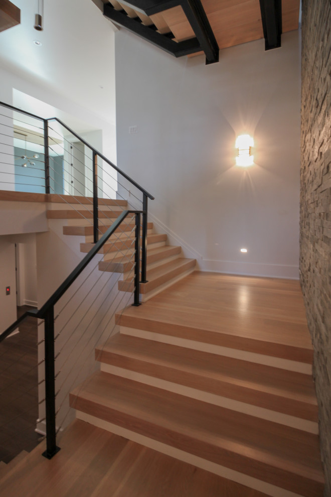 Exemple d'un grand escalier flottant éclectique avec des marches en bois, un garde-corps en métal et un mur en parement de brique.