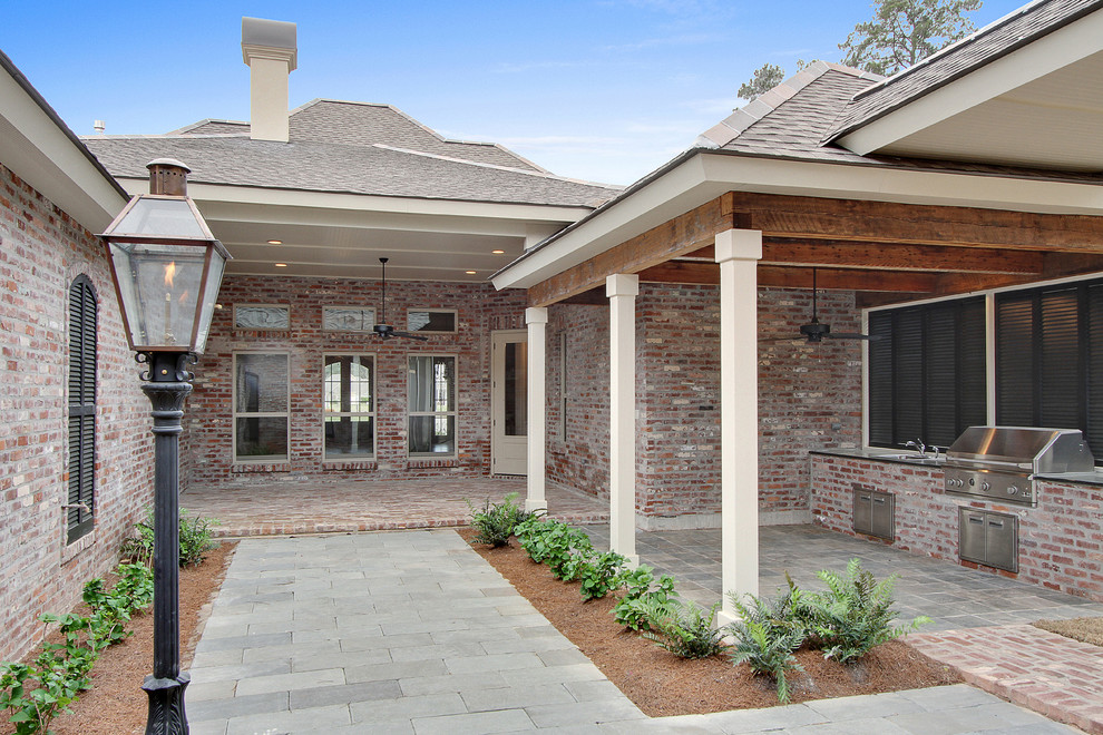 This is an example of a traditional backyard verandah in New Orleans with an outdoor kitchen, brick pavers and a roof extension.