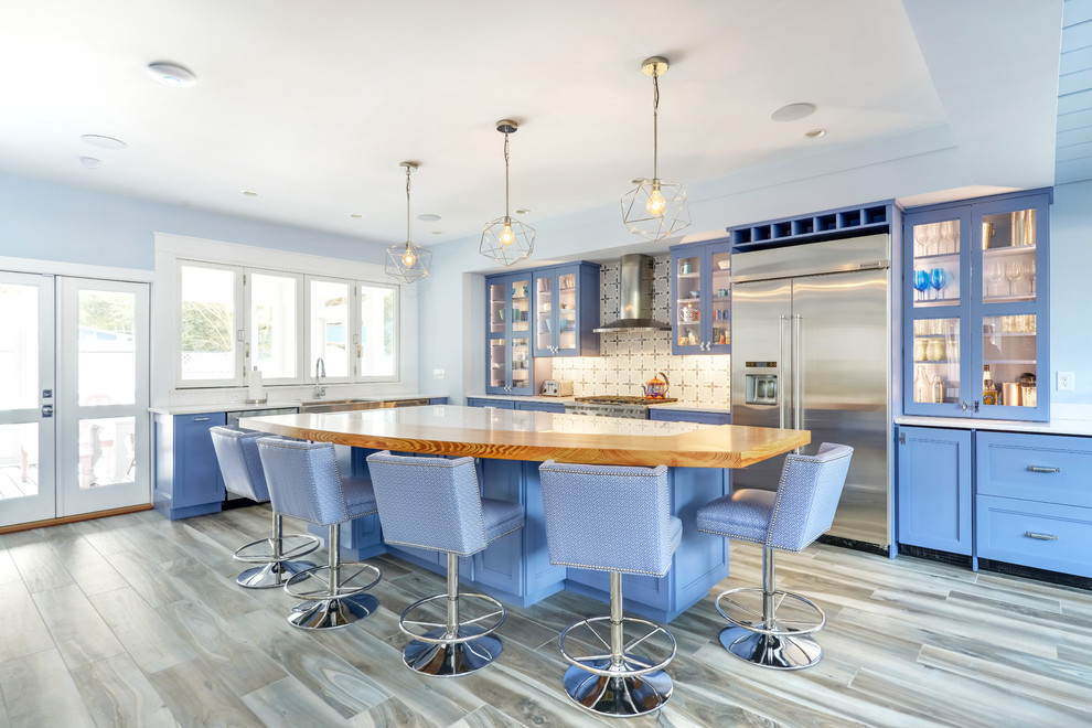 Beach style kitchen in Other with a farmhouse sink, beaded inset cabinets, blue cabinets, wood benchtops, white splashback, stainless steel appliances, medium hardwood floors, brown floor and brown benchtop.