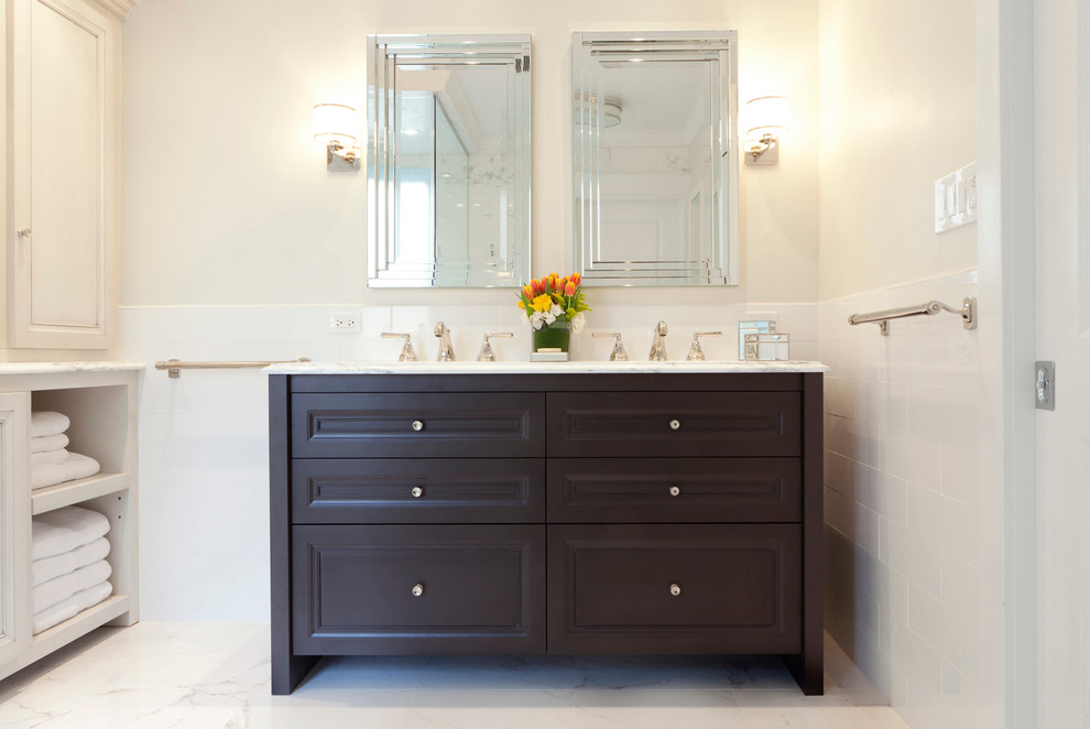 This is an example of a mid-sized traditional master bathroom in Philadelphia with furniture-like cabinets, dark wood cabinets, a corner shower, a two-piece toilet, white tile, ceramic tile, white walls, marble floors, an undermount sink, marble benchtops, white floor and a hinged shower door.
