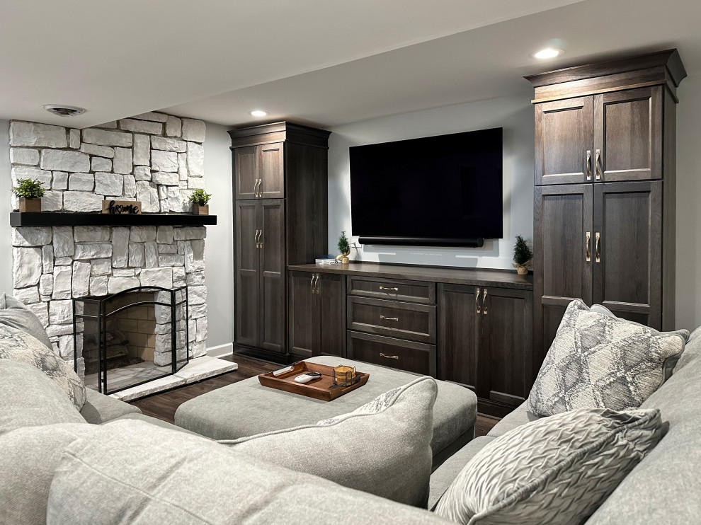 Photo of a medium sized classic fully buried basement in Chicago with a home bar, grey walls, vinyl flooring, a standard fireplace, a stone fireplace surround and brown floors.
