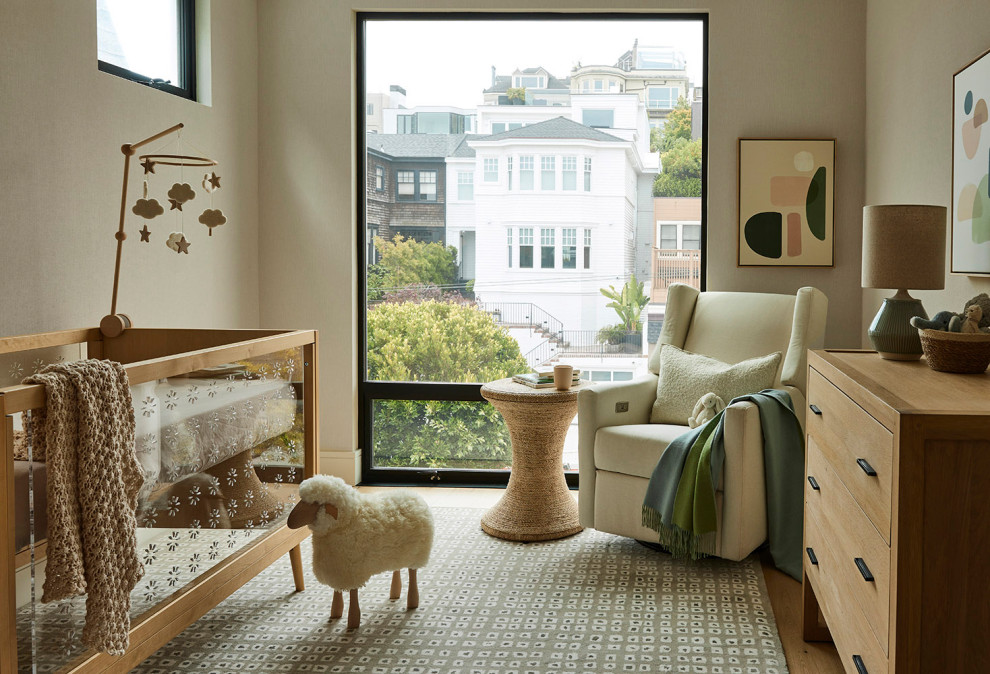 Foto de habitación de bebé neutra actual de tamaño medio con paredes beige y suelo de madera en tonos medios