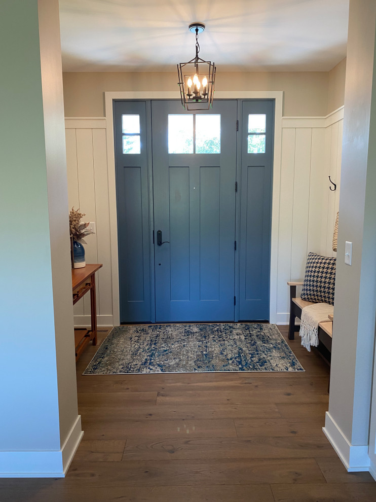 Immagine di un ingresso di medie dimensioni con pareti beige, pavimento in legno massello medio, una porta singola, una porta blu, pavimento marrone e boiserie