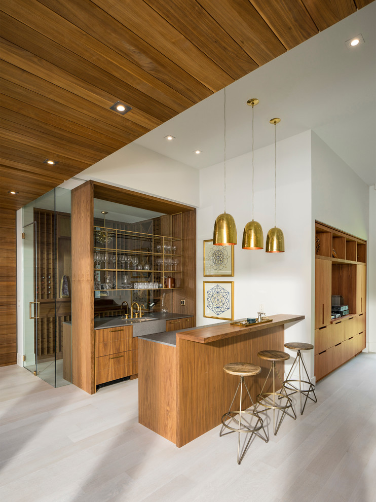 This is an example of a mid-sized contemporary galley wet bar in Salt Lake City with flat-panel cabinets, medium wood cabinets, quartz benchtops, light hardwood floors, glass sheet splashback and grey floor.