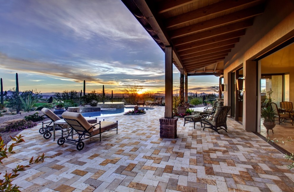 This is an example of a mid-sized eclectic backyard patio in Phoenix with natural stone pavers and a roof extension.