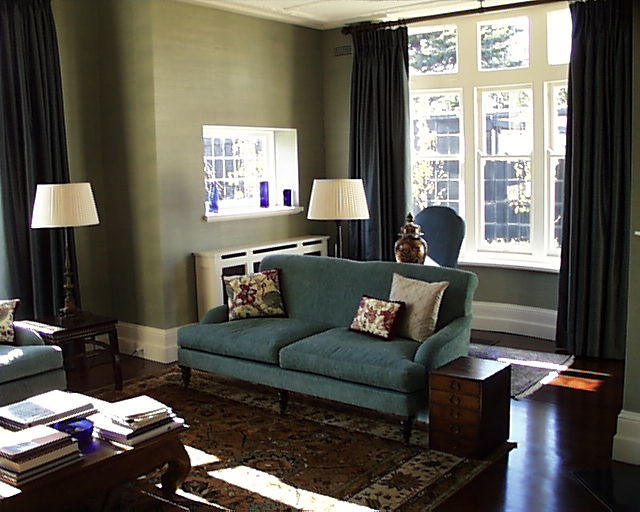 Expansive beach style enclosed living room in Melbourne with green walls, dark hardwood flooring, a corner fireplace, a plastered fireplace surround and a concealed tv.