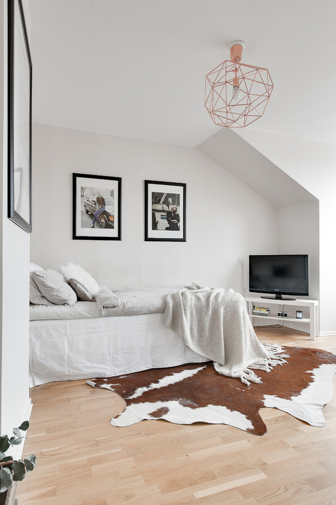 Photo of a mid-sized scandinavian master bedroom in Stockholm with white walls, light hardwood floors and no fireplace.