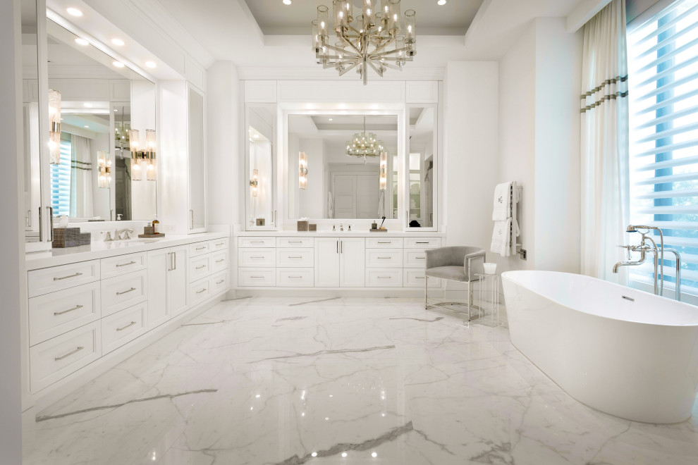 Пример оригинального дизайна: большая главная ванная комната в стиле неоклассика (современная классика) с фасадами в стиле шейкер, белыми фасадами, отдельно стоящей ванной, унитазом-моноблоком, белой плиткой, керамогранитной плиткой, белыми стенами, полом из керамогранита, врезной раковиной, мраморной столешницей, белым полом, душем с распашными дверями, белой столешницей, тумбой под две раковины, встроенной тумбой и кессонным потолком