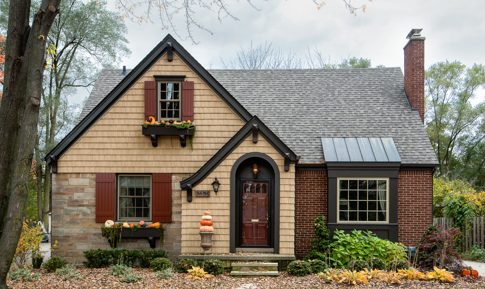 Example of a small classic beige two-story brick gable roof design in Detroit with a shingle roof