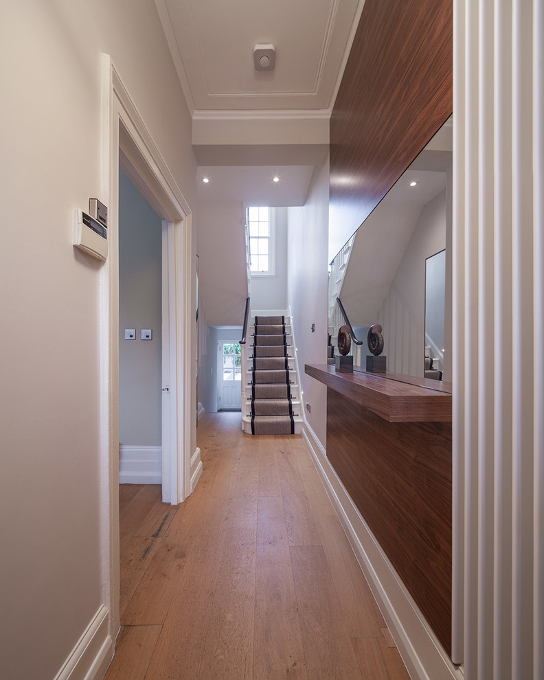 Photo of a mid-sized modern hallway in London with white walls and medium hardwood floors.