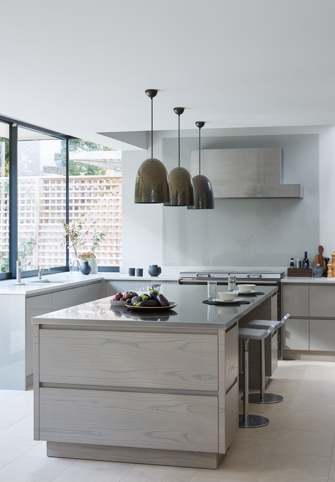 Photo of a large contemporary l-shaped open plan kitchen in London with an integrated sink, flat-panel cabinets, beige cabinets, quartzite benchtops, stainless steel appliances, ceramic floors, multiple islands, beige floor and white benchtop.