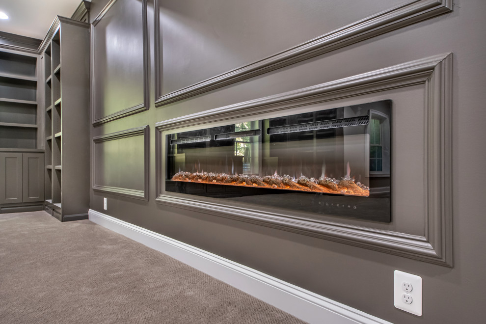 This is an example of a large classic walk-out basement in DC Metro with a home bar, black walls, carpet, brown floors and a hanging fireplace.