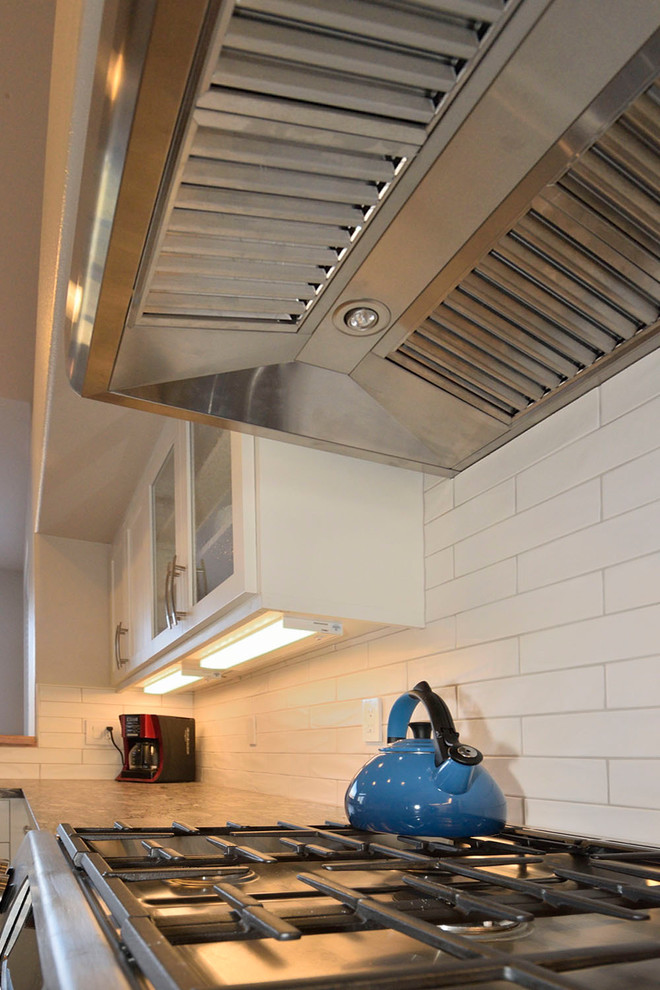 Example of a mid-sized trendy medium tone wood floor eat-in kitchen design with an undermount sink, shaker cabinets, white cabinets, granite countertops, white backsplash, ceramic backsplash and stainless steel appliances