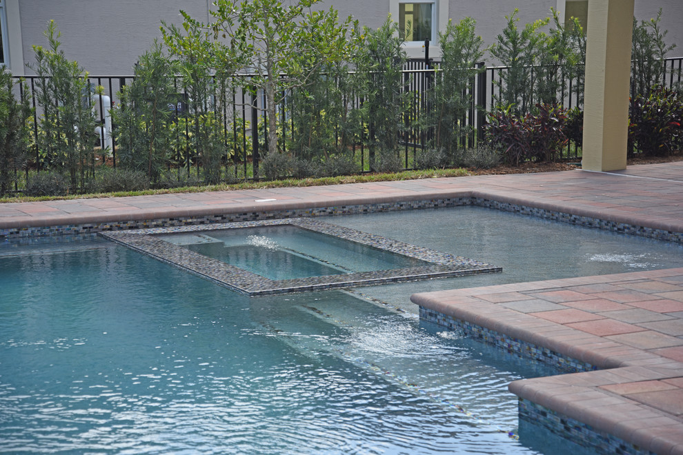 Example of a mid-sized backyard stone and rectangular infinity pool design in Miami