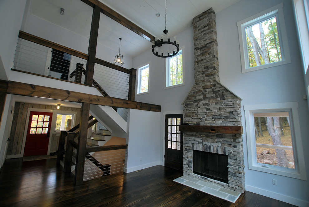 This is an example of a large country open concept family room in New York with white walls, dark hardwood floors, a standard fireplace and a stone fireplace surround.