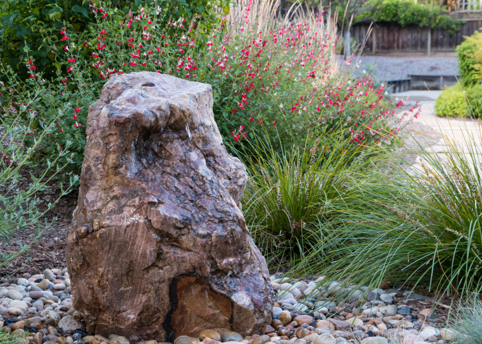 This is an example of a backyard full sun xeriscape in San Francisco with a water feature and natural stone pavers.