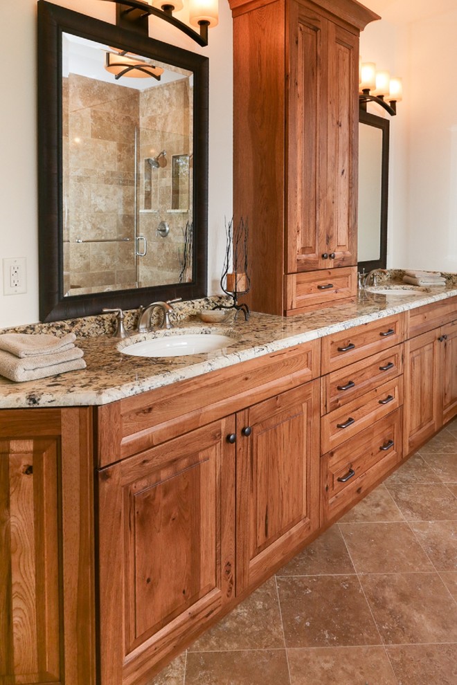 Inspiration for a large arts and crafts master bathroom in Other with raised-panel cabinets, medium wood cabinets, a corner shower, beige tile, stone tile, white walls, porcelain floors, an undermount sink, granite benchtops, brown floor, a hinged shower door and multi-coloured benchtops.