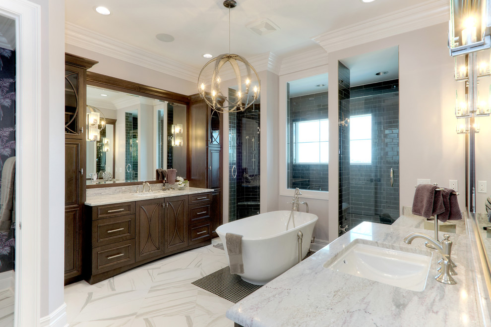 Photo of a mid-sized transitional master bathroom in Tampa with recessed-panel cabinets, dark wood cabinets, a freestanding tub, an alcove shower, a two-piece toilet, gray tile, subway tile, beige walls, marble floors, an undermount sink, quartzite benchtops, white floor and a hinged shower door.