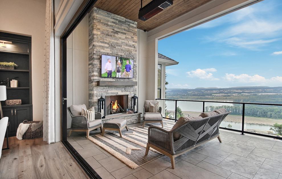 Photo of an expansive country balcony in Portland with with fireplace, a roof extension and glass railing.