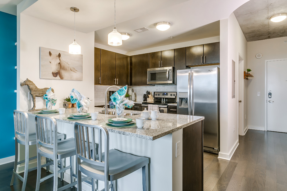 Inspiration for a small transitional medium tone wood floor and brown floor kitchen remodel in Dallas with a double-bowl sink, glass-front cabinets, dark wood cabinets, granite countertops, white backsplash, marble backsplash, stainless steel appliances and an island