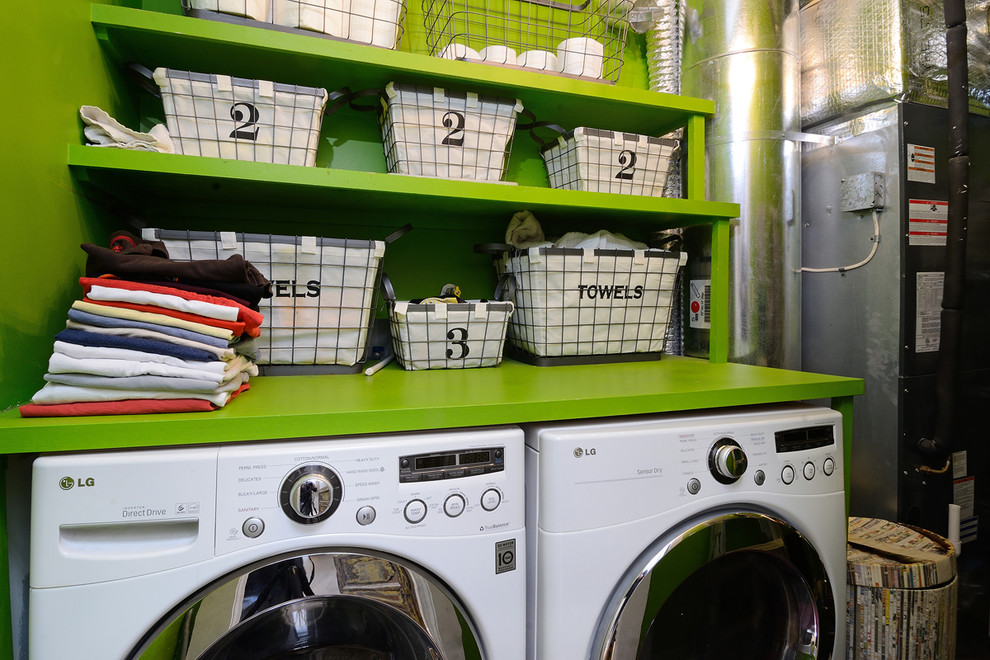 This is an example of an eclectic laundry room in New York with open cabinets, green cabinets, green walls, a side-by-side washer and dryer and green benchtop.