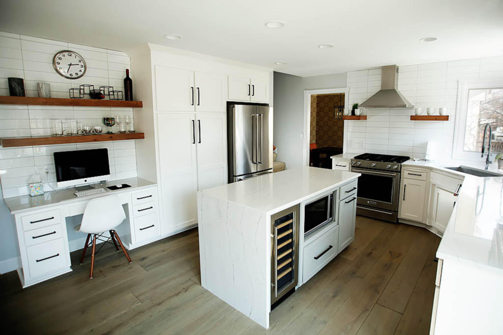 Kitchen - mid-sized transitional u-shaped medium tone wood floor and brown floor kitchen idea in Omaha with an undermount sink, shaker cabinets, white cabinets, quartzite countertops, white backsplash, ceramic backsplash, stainless steel appliances, an island and white countertops
