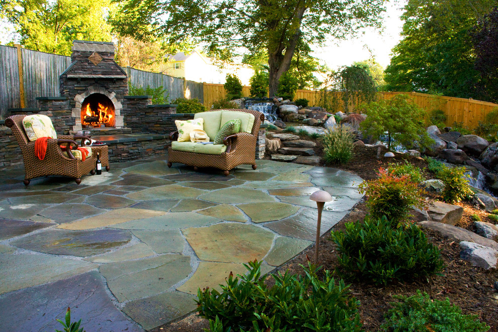 This is an example of a large traditional backyard patio in DC Metro with a water feature and natural stone pavers.