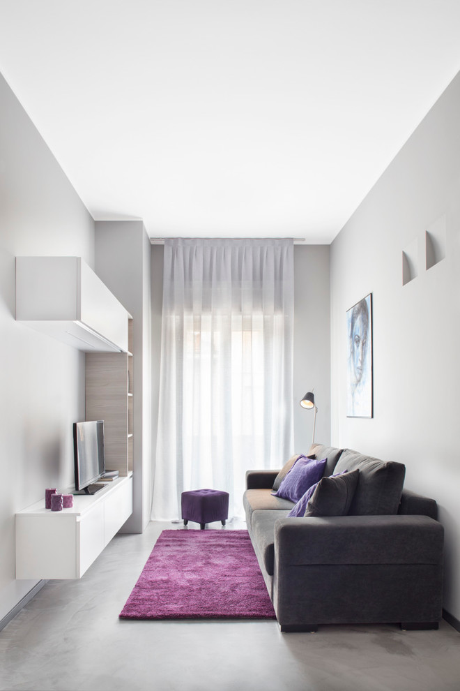 This is an example of a small contemporary family room in Milan with grey walls, concrete floors and a freestanding tv.