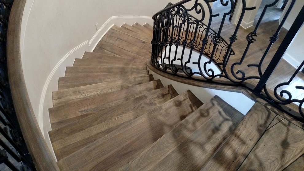 Mediterranean wood curved staircase in Houston with wood risers.