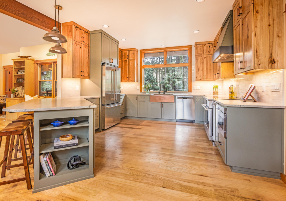 Eat-in kitchen - large rustic u-shaped light wood floor and brown floor eat-in kitchen idea with a farmhouse sink, shaker cabinets, quartzite countertops, gray backsplash, ceramic backsplash, stainless steel appliances, a peninsula and gray countertops