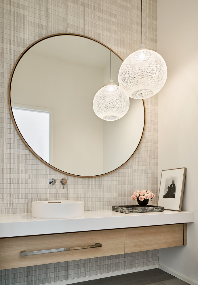 Example of a mid-sized trendy porcelain tile and gray floor powder room design in Dallas with flat-panel cabinets, light wood cabinets, a vessel sink, quartz countertops, white countertops and gray walls