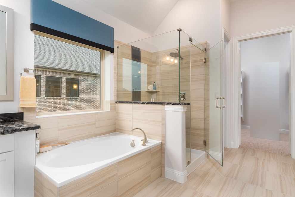 Inspiration for a mid-sized traditional master bathroom in Houston with recessed-panel cabinets, white cabinets, a drop-in tub, a corner shower, beige tile, ceramic tile, light hardwood floors, an undermount sink, granite benchtops, beige floor, a hinged shower door, black benchtops and beige walls.