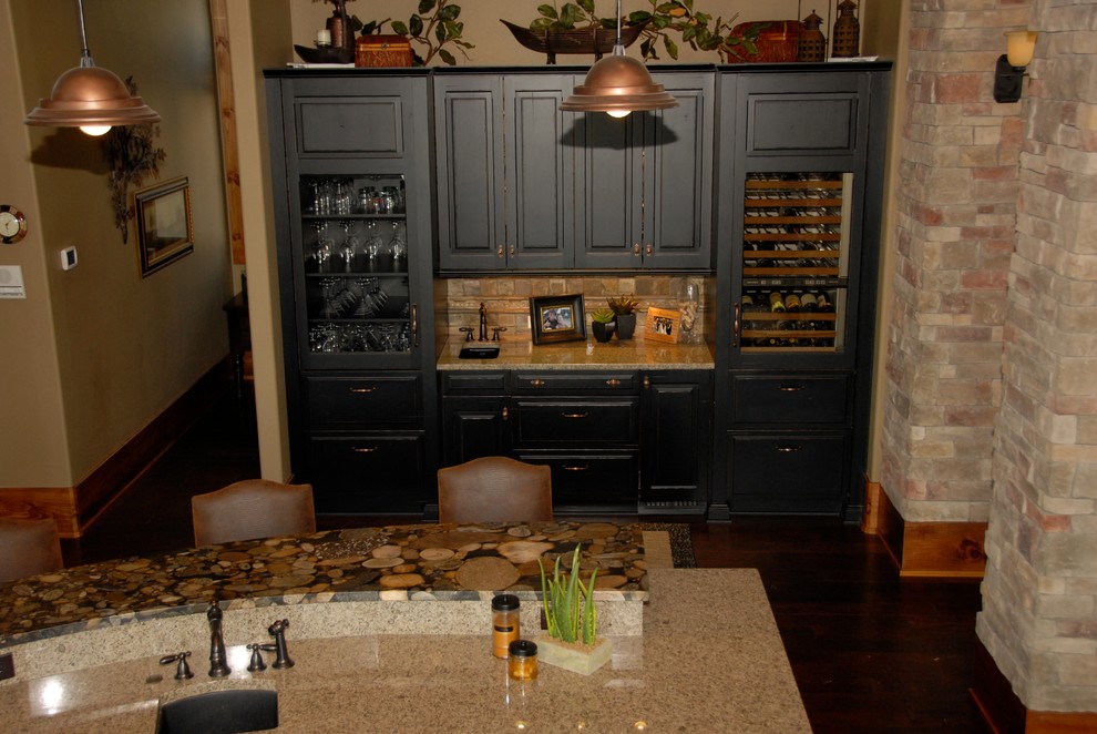 Mid-sized country single-wall eat-in kitchen in Kansas City with raised-panel cabinets, black cabinets, beige splashback, a single-bowl sink, travertine splashback, panelled appliances, dark hardwood floors, multiple islands and brown floor.