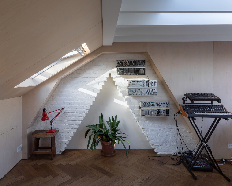 Photo of a medium sized eclectic home studio in London with medium hardwood flooring, a built-in desk, brown floors, exposed beams, wood walls and a chimney breast.