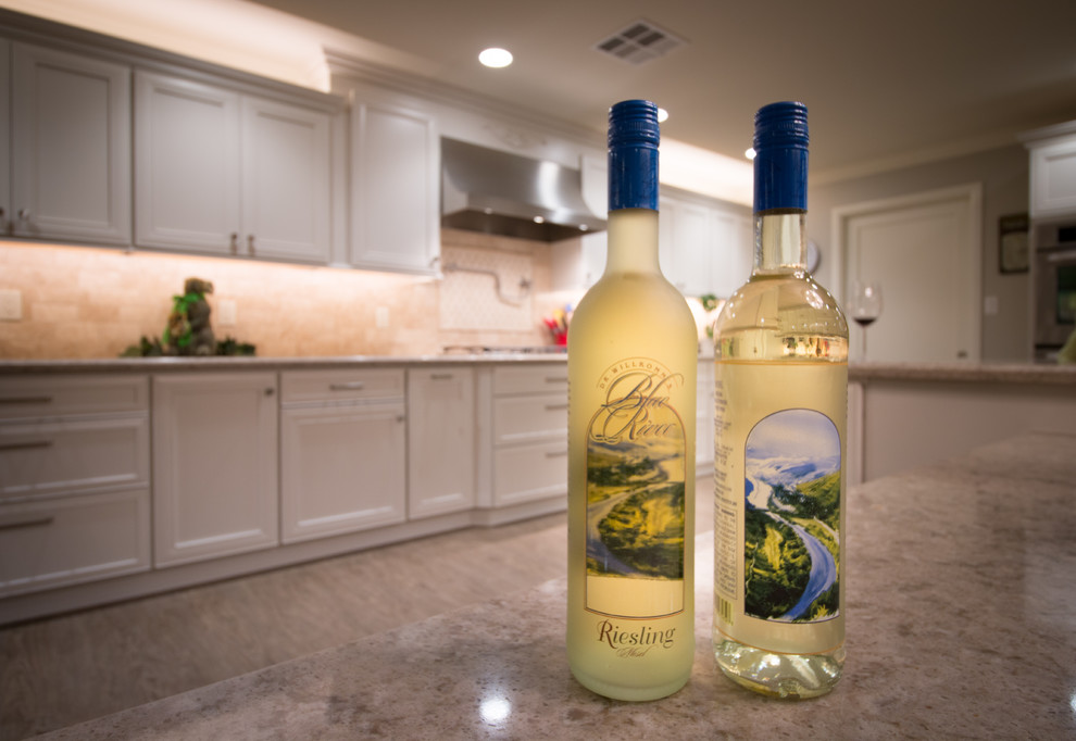 Inspiration for a huge transitional open concept kitchen remodel with a farmhouse sink, recessed-panel cabinets, white cabinets, quartz countertops, beige backsplash, stone tile backsplash, stainless steel appliances and an island