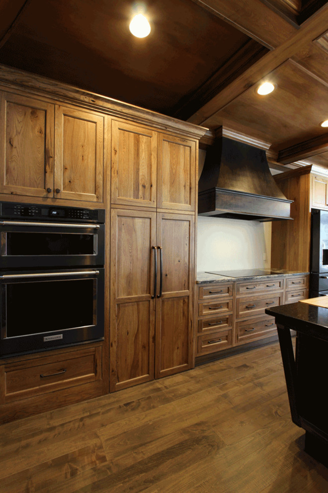 Mountain style brown floor open concept kitchen photo with an undermount sink, flat-panel cabinets, medium tone wood cabinets, quartz countertops, stainless steel appliances and two islands