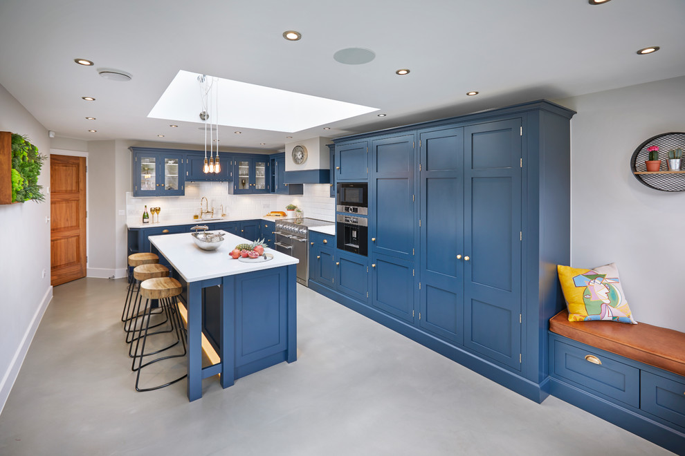 Photo of a large traditional l-shaped eat-in kitchen in Other with an integrated sink, shaker cabinets, blue cabinets, quartzite benchtops, white splashback, subway tile splashback, stainless steel appliances, concrete floors, with island, grey floor and white benchtop.